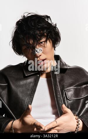 Uomo asiatico con intonaco sul naso che posa in una giacca di pelle. Stile sicuro. Foto Stock