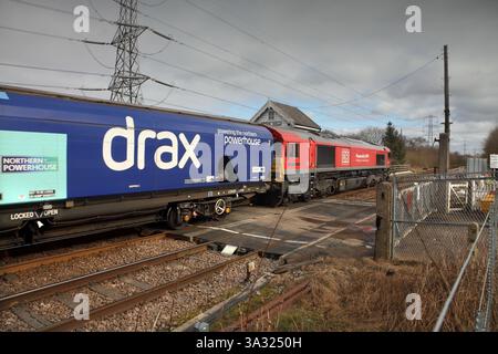DB Cargo Class 66 loco 66077 passa il passaggio a livello di Medge Hall con i binari 1038 4R50 Milford al treno a biomassa vuoto Immingham il 25/2/25. Foto Stock