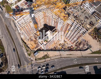 Il cantiere mette in mostra materiali e attrezzature vivaci sotto la luce del sole in un'area urbana. Vista dall'alto verso il basso dell'antenna Foto Stock