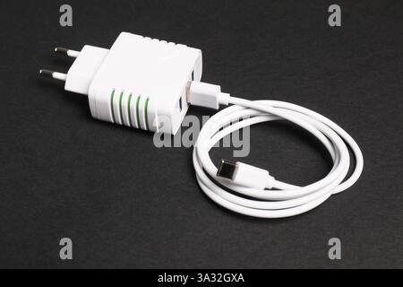 Adattatore di alimentazione USB con cavo di ricarica su sfondo nero, primo piano Foto Stock