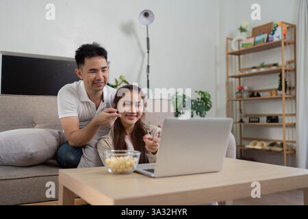 Serata al cinema e insieme. Una coppia si diverte a guardare un film leggero mentre si nutrono a vicenda dei popcorn. Foto Stock