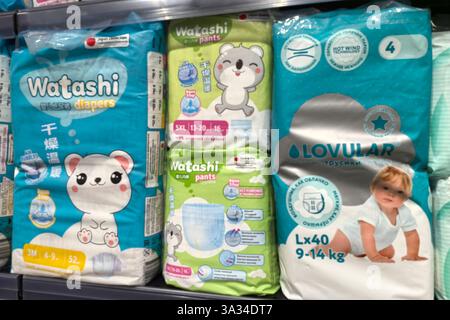 Bobruisk, Bielorussia - 2 marzo 2025: Pannolini confezionati in modo brillante sono disposti sugli scaffali di un corridoio di negozi, con design adorabili. I genitori sfogliano le opzioni a. Foto Stock