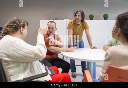 Un gruppo di persone con disabilità mentali partecipa a una discussione con un operatore sanitario presso un centro di supporto. Foto Stock
