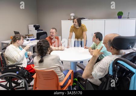 Un gruppo di persone con disabilità mentali partecipa a una discussione con un operatore sanitario presso un centro di supporto. Foto Stock