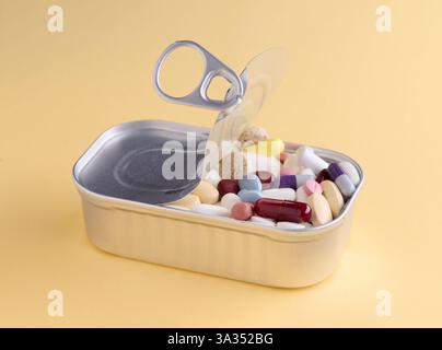 L'alluminio può essere aperto per rivelare una varietà di pillole colorate, che simboleggiano i prodotti farmaceutici e la sanità, isolate su sfondo giallo. Foto Stock