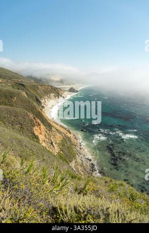 Splendida costa del Big Sur con torreggianti scogliere, paesaggi verdi e le onde dell'Oceano Pacifico che si infrangono contro la costa. Un vivido mix di terra A. Foto Stock