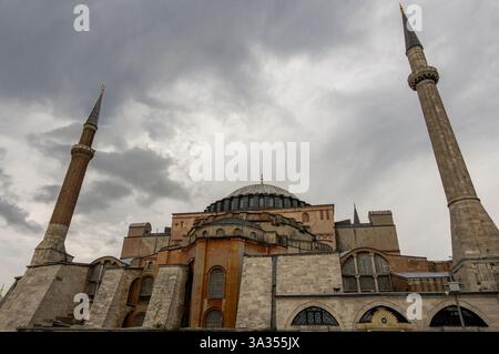 Vista spettacolare di Hagia Sophia, con nuvole scure che incombono sui suoi maestosi minareti e cupole. Questo iconico simbolo di Istanbul è una testimonianza Foto Stock