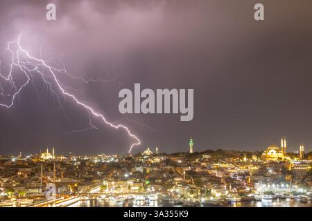 Una suggestiva scena di fulmini che si diramano sullo skyline notturno di Istanbul, evidenziando monumenti storici in mezzo a un vibrante bagliore della città. Foto Stock