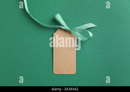 Etichetta vuota con arco a nastro su sfondo verde, vista dall'alto Foto Stock