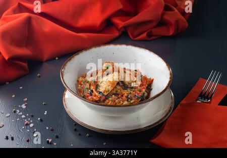 Chakhokhbili - pollo stufato con pomodori e cipolle su sfondo scuro. Menu per un ristorante georgiano. Menu del ristorante. Foto Stock