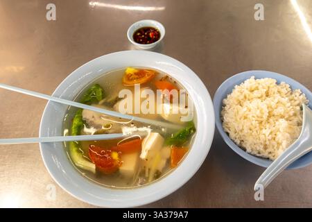 Zuppa di pollo e tofu, accompagnata da un lato di riso e un piccolo piatto di salsa, Warung Nasi hai San Cafe, Johor Bahru, Malesia, asia Foto Stock
