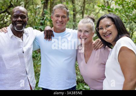 Amici anziani felici che si godono la natura passeggiano insieme nella lussureggiante foresta verde Foto Stock