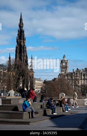Persone che godono di un po' di sole invernale e viste del Monumento Scott e del Balmoral Hotel dal tumulo nella New Town di Edimburgo. Foto Stock