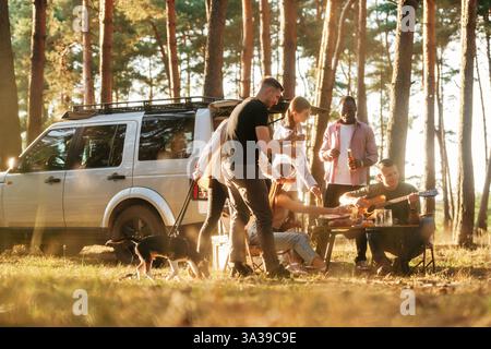 Divertirsi vicino alla macchina. Un gruppo di amici si diverte insieme nella foresta. Foto Stock