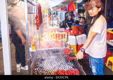 grill, spiedini, venditrice di Street food a Jalan Alor, Bukit Bintang, una popolare strada di cibo Kuala Lumpur Malesia Foto Stock