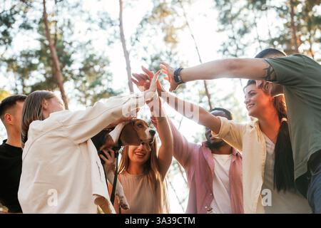 Con il cane. Un gruppo di amici si diverte insieme nella foresta. Foto Stock