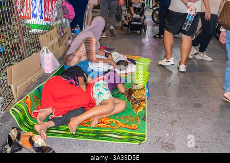 Famiglia senzatetto, che dorme su un tappeto per strada, secchio di mendicanti, centro di Kuala Lumpur, Malesia Foto Stock