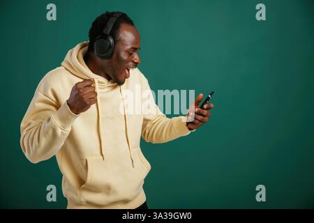 Ascoltare la musica, ballare. Un uomo afroamericano si trova sullo sfondo verde nello studio. Foto Stock