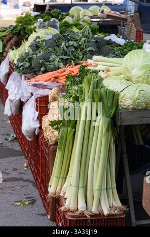 Verdure verdi fresche e croccanti: Lattuga, spinaci, cavoli, porri, e le erbe sono splendidamente disposte in un vivace mercato biologico degli agricoltori Foto Stock