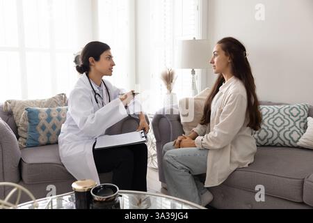 Una seria dottoressa indiana che parla con una giovane donna Foto Stock