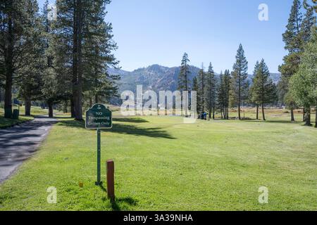Un tee box su un pittoresco campo da golf di montagna. C'è un cartello che dice "No Trespassing, solo golfisti” Foto Stock