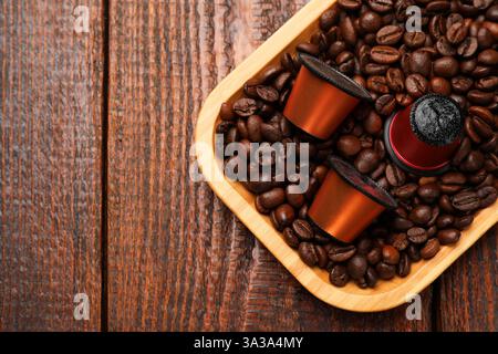 Capsule e chicchi di caffè su un tavolo di legno, vista dall'alto. Spazio per il testo Foto Stock