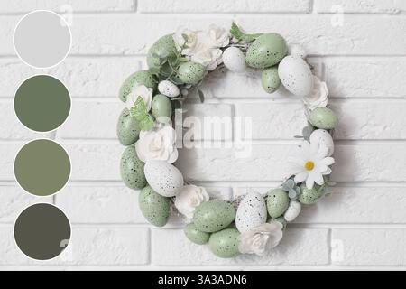 Corona di Pasqua con uova e fiori su una parete di mattoni bianchi. Diversi modelli di colore Foto Stock