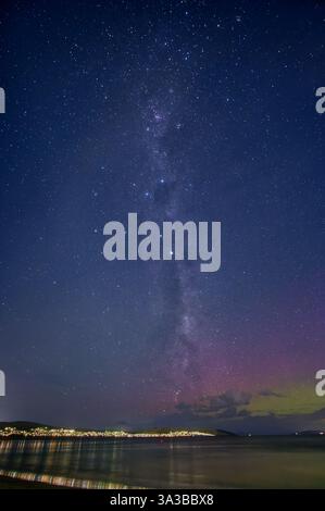 Via Lattea che si innalza nel cielo limpido con stelle e luci della città riflesse nel fiume Derwent con Aurora Australis Hobart Tasmania Australia Foto Stock