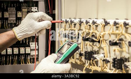 Un ingegnere elettrico verifica regolarmente il funzionamento dell'armadio elettrico per la manutenzione. Foto Stock