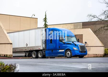 Semi-camion di lunga percorrenza blu grande carro industriale con cabina estesa per il riposo del conducente del veicolo e scarico semi-rimorchio di furgoni asciutti consegnato in posizione di carico Foto Stock