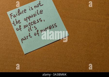 Una nota adesiva azzurra è posta su una superficie marrone, con una citazione motivazionale sul fallimento e sul successo. Foto Stock