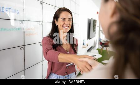 Allegra donna leader d'affari che stringe la mano a una collega Foto Stock