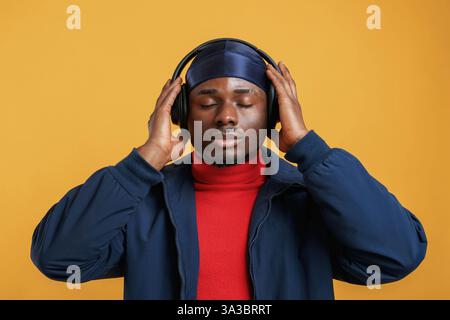 Con le cuffie, ascolta la musica. Bell'uomo nero e' nello studio su sfondo giallo. Foto Stock