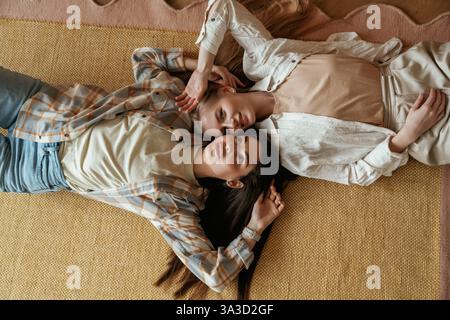 Sdraiati sul pavimento. Due giovani amiche felici sono al chiuso. Foto Stock