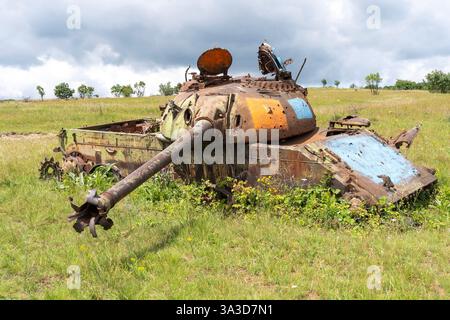 Un vecchio carro armato russo distrutto su un campo erboso Foto Stock