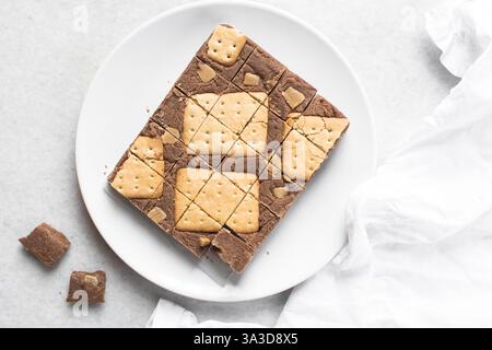 Vista dall'alto del cioccolato fudge con biscotti e pezzi di fudge su un piatto bianco, vista dall'alto del cioccolato alle nocciole tagliato a pezzi Foto Stock