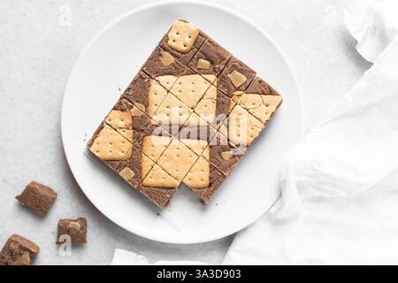 Vista dall'alto del cioccolato fudge con biscotti e pezzi di fudge su un piatto bianco, vista dall'alto del cioccolato alle nocciole tagliato a pezzi Foto Stock