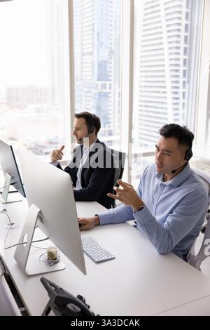 Un serio e impegnato agente di telemarketing asiatico che parla con il cliente Foto Stock
