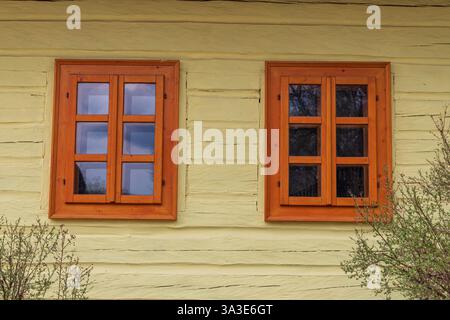 Due finestre di una tradizionale casa di legno gialla a Vlkolínec, patrimonio dell'umanità dell'UNESCO Foto Stock