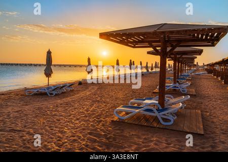 Spiaggia tranquilla a Hurghada in Egitto con ombrelloni in legno all'alba in estate Foto Stock