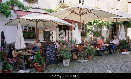 Grazioso patio del ristorante con gente che gusta cibo e bevande in un villaggio medievale in Germania Foto Stock