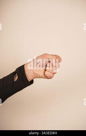 Lo sfondo semplice migliora la potenza della posa. Un simbolo senza tempo di coraggio. La mano forma un pugno forte, simboleggiando forza e protesta Foto Stock