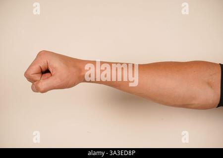 Lo sfondo semplice migliora la potenza della posa. Un simbolo senza tempo di coraggio. La mano forma un pugno forte, simboleggiando forza e protesta Foto Stock