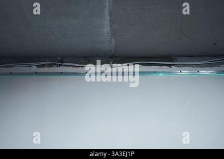 Una livella laser verde posizionata su una parete in cemento proietta linee luminose sul soffitto per misurazioni impeccabili. Foto Stock