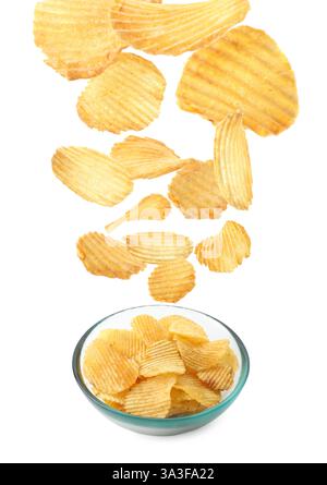 Gustose patatine che cadono nella ciotola su sfondo bianco Foto Stock
