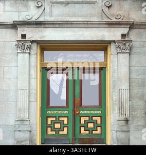 Doppie porte in verde e oro dal design complesso all'interno di una storica facciata in pietra calcarea, caratterizzata da colonne corinzie ornate. Foto Stock