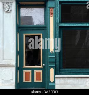 Vetrina vintage con una porta in legno verde con finiture ornamentali e dettagli architettonici decorativi che riflettono il fascino storico. Foto Stock