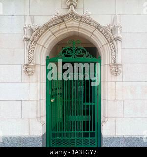 Cancello in ferro battuto verde collocato all'interno di un arcata gotica decorata, caratterizzato da intricate incisioni in pietra su una facciata storica di un edificio a Chicago. Foto Stock
