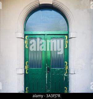 Un'elegante porta in legno verde con dettagli dorati incastonata in una cornice ad arco in pietra, che riflette il fascino architettonico storico di Kraków, Polonia Foto Stock