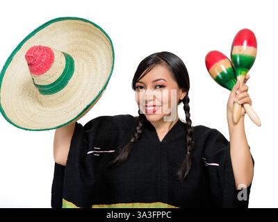 Una donna messicana sorridente che indossa un poncho colorato e un cappello gioca a maracas, isolata su sfondo bianco. Foto Stock